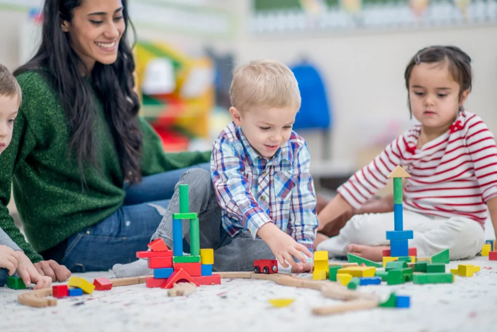 A vibrant classroom scene filled with children engaged in various play-based learning activities such as building blocks, art crafts, and outdoor exploration